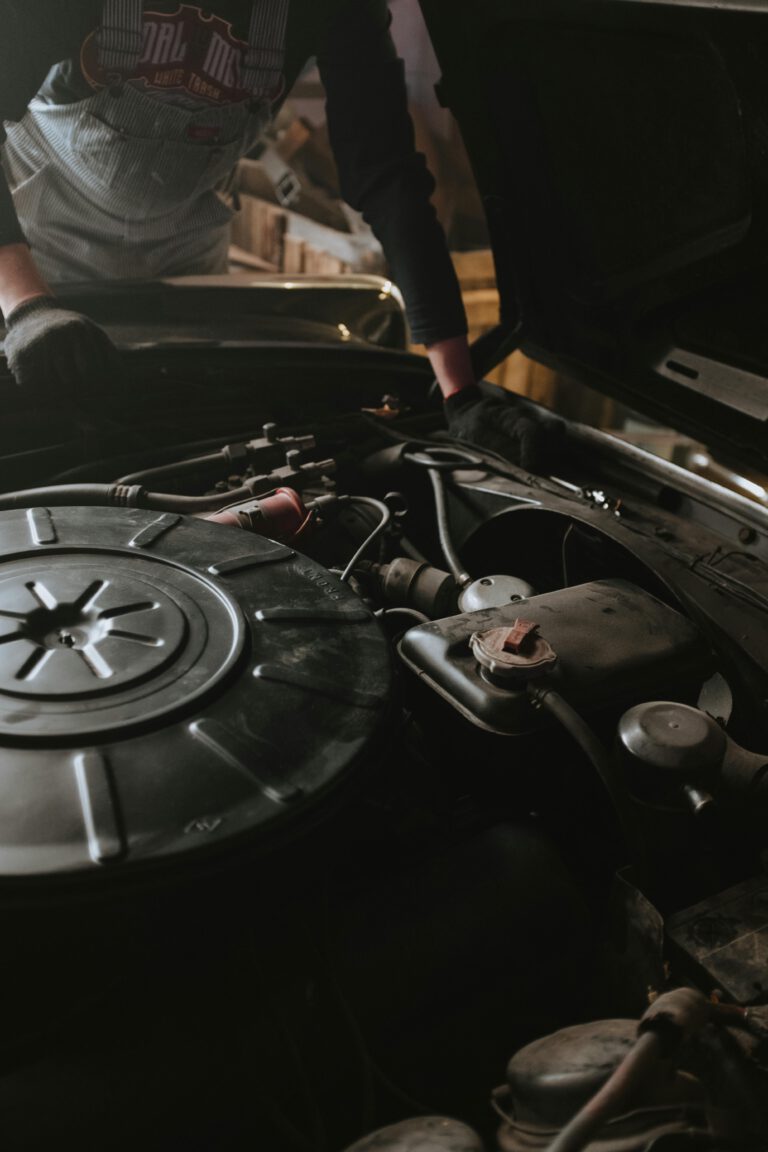 Close-up of a mechanic repairing a car engine in a garage setting.